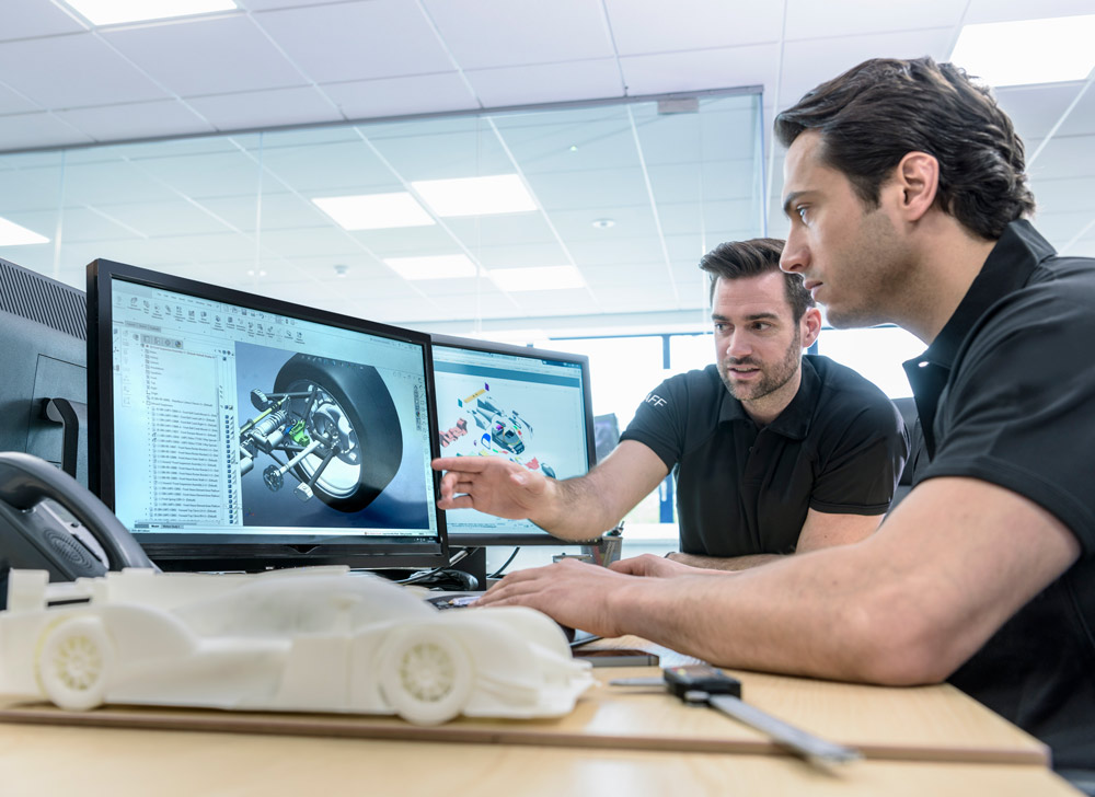 Två personer kollar på en CAD design på datorn