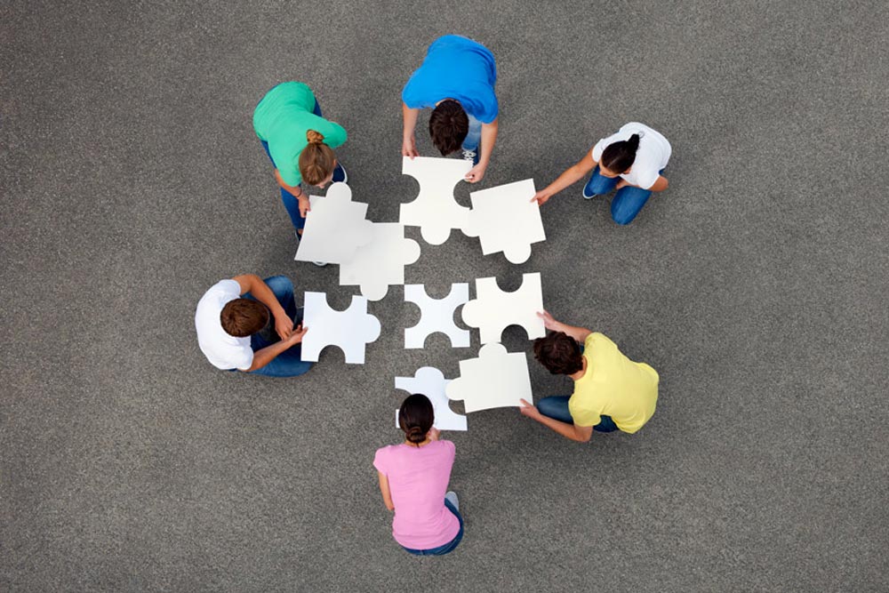 Personer lägger stora pusselbitar utomhus